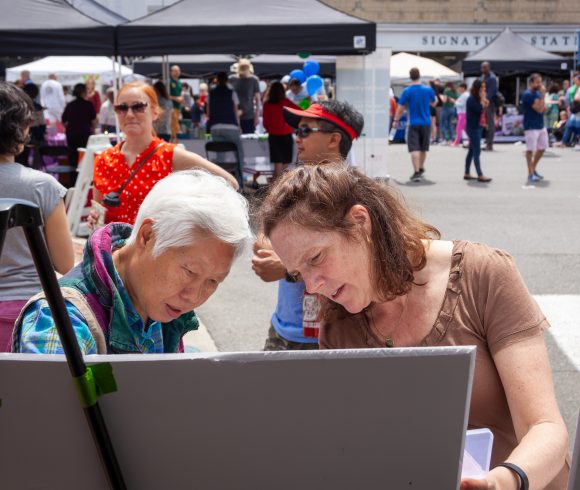 Two people looking at a presentation board at an outdoor festival